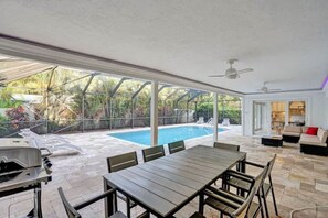 A spacious patio with a pool, outdoor seating, and a view of the surrounding greenery.