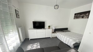Ett modernt sovrum med en soffa, en säng, en tv och ett nattduksbord.