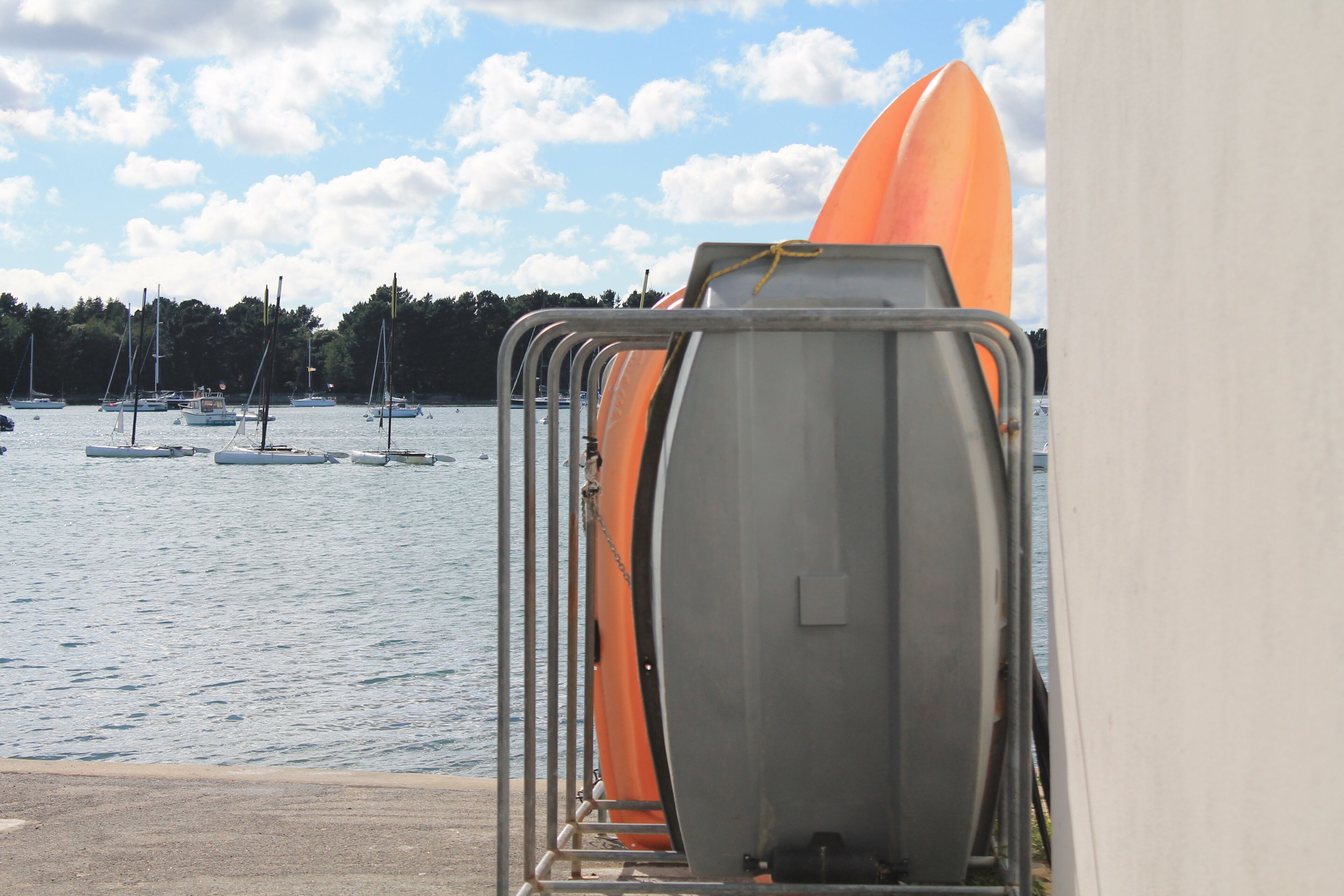 A harbor with boats and a metal rack holding a surfboard.