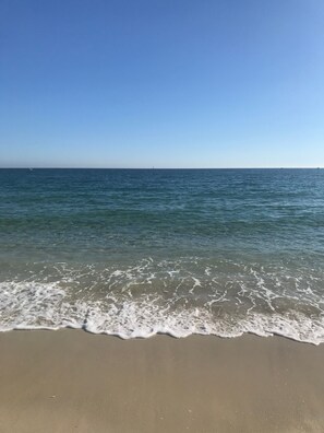 Une plage avec une eau claire et un horizon bien visible.