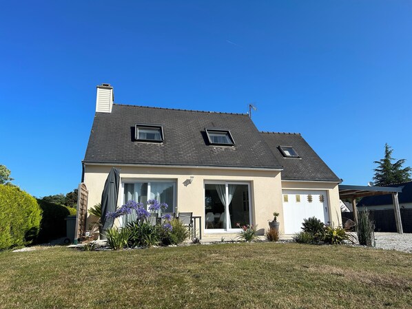 A two-story house with a dark roof, large windows, and a covered patio area. - Peaceful house with garden 3 minutes from the beach (Combrit)