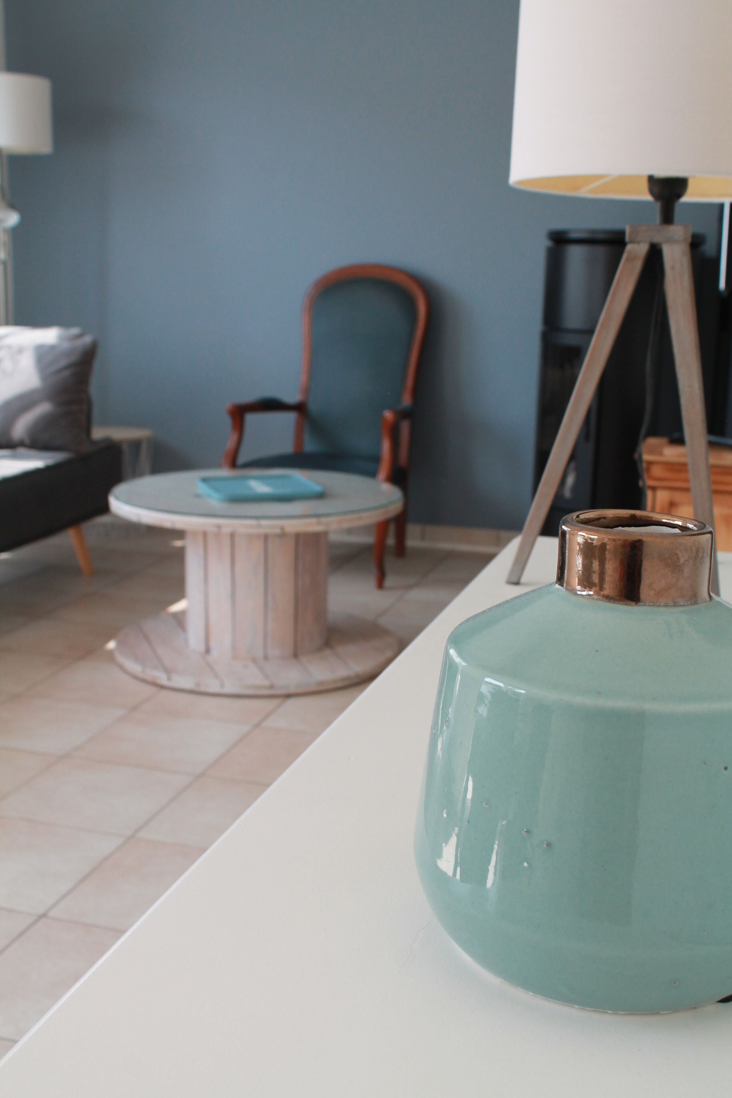 A room with a round table, a chair, a sofa, and a lamp.