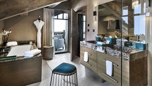 A modern bathroom with a large mirror, a bathtub, and a vanity with a marble countertop. - LYS MARTAGON (Courchevel)