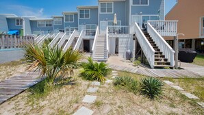 Eine Reihe von Strandhütten mit Holzdecks und Treppen, die zum Eingang führen.