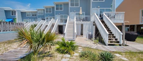 A row of beachside cabins with wooden decks and stairs leading to the entrance.