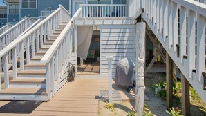 Eine Holzterrasse mit weißen Geländern, die zu einem überdachten Bereich mit Rollstuhl führt.