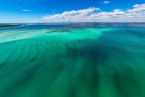 An aerial view of a coastal area with clear turquoise waters and a sandy beach. - Cheerful 1BR on the Island w/ King Bed (Navarre Beach)