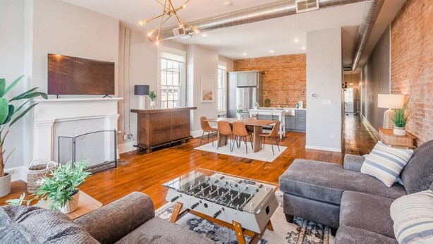 Ein modernes Wohnzimmer mit Kicker, Kamin und einer Küche im Hintergrund.