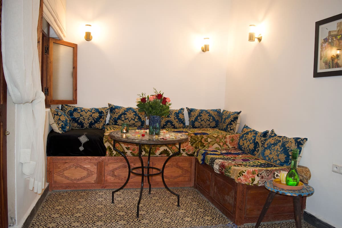 A cozy room with a sofa, a small round table, and a patterned rug.