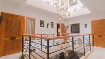 A spacious interior with a high ceiling, wooden doors, and a balcony with a railing.
