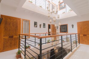 A spacious interior with a high ceiling, wooden doors, and a balcony with a railing. - Le Khan Mogador (Essaouira)
