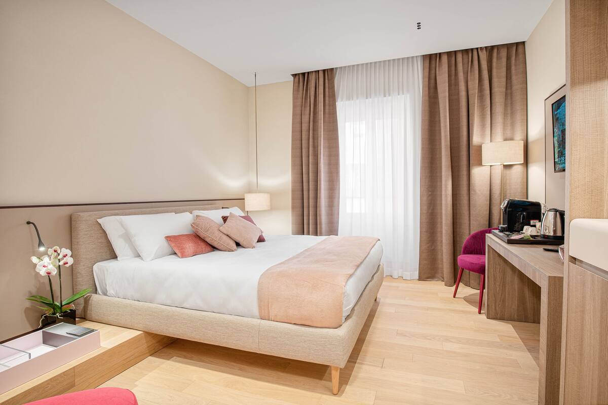A modern hotel room with a large bed, a desk, and a chair.
