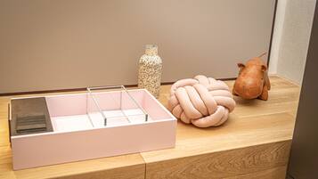 A wooden table with a pink storage box, a decorative vase, and a plush toy.
