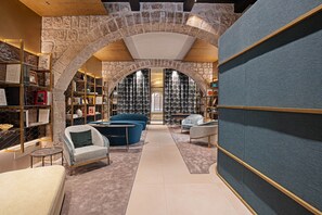 A modern interior with a stone archway, seating areas, and a large bookshelf.