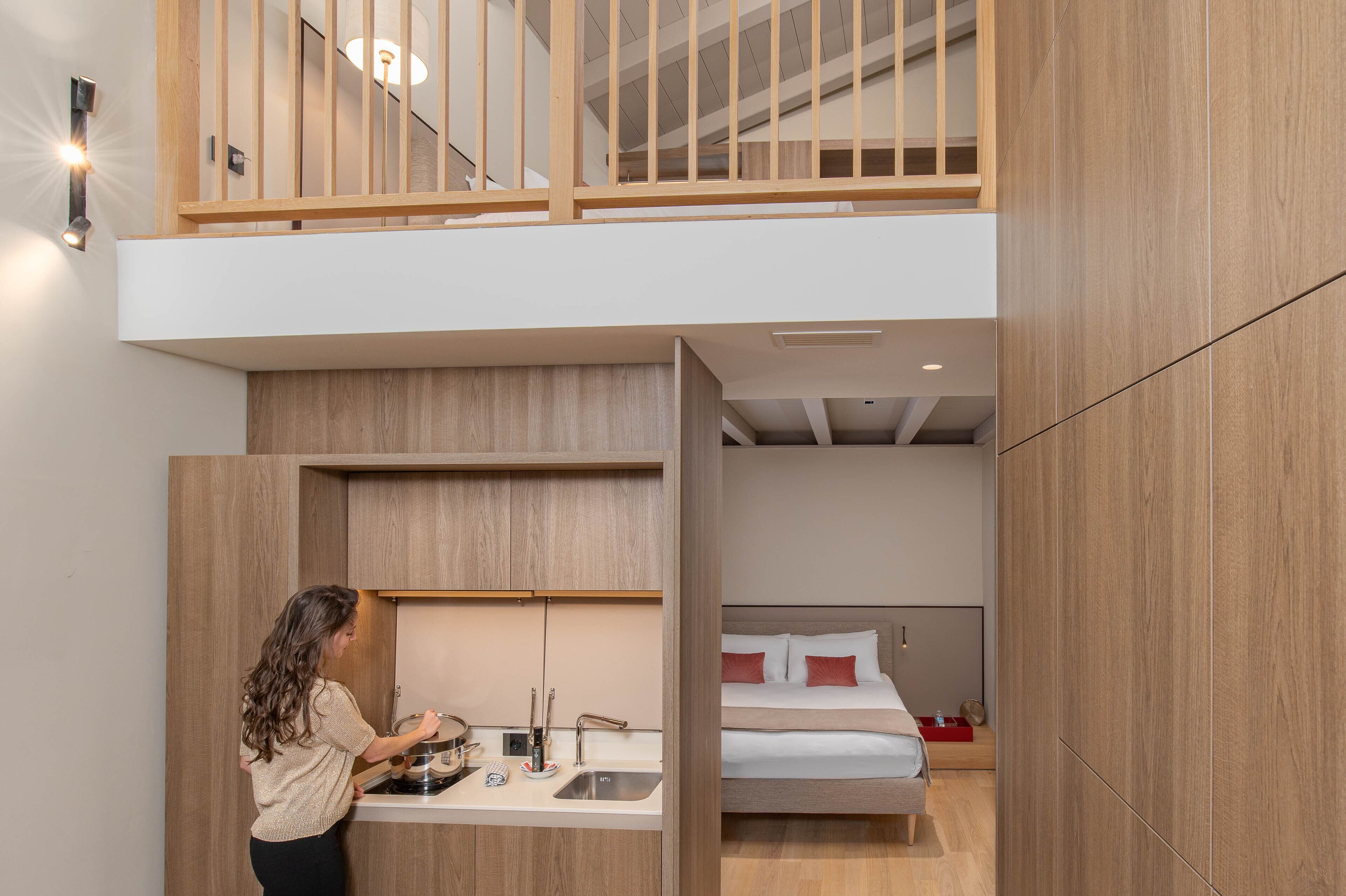 A compact hotel room with a kitchenette, a bed, and a small bathroom.