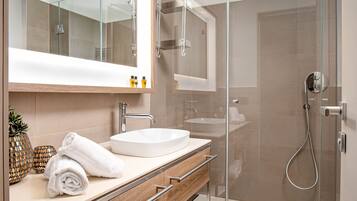 A modern bathroom with a glass-enclosed shower, a large mirror, and a wooden vanity with a sink and towel rack.
