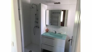Ein Badezimmer mit Waschbecken aus Glas, einem Spiegel und einer Dusche.