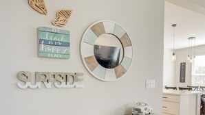 Une cuisine moderne avec une console en bois, des œuvres d’art décoratives au mur et un miroir rond.