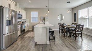 Une cuisine moderne dotée d’un îlot central, d’appareils électroménagers en acier inoxydable et d’un revêtement de sol en bois.