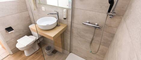 A modern bathroom with a glass shower enclosure, a white sink, and a toilet.