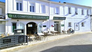 A white building with outdoor seating and a bicycle parked outside. -  Hotel le Coureau (Saint-Trojan-les-Bains)