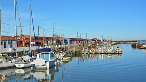 A marina with boats docked, a restaurant, and a pier extending into the water. -  Hotel le Coureau (Saint-Trojan-les-Bains)