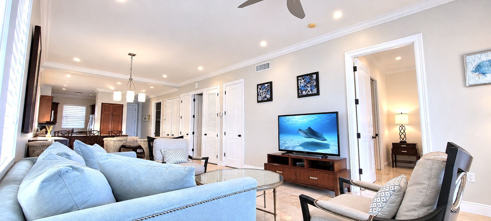 A living room with a sofa, chairs, a TV, and a dining area in the background.