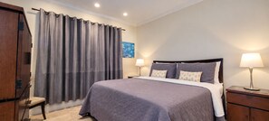 Un dormitorio con cama, dos lámparas de noche, una silla y un armario.