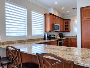 A kitchen with granite countertops, wooden cabinets, a microwave, and a coffee maker.