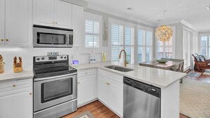 Una cocina moderna con armarios blancos, electrodomésticos de acero inoxidable y una isla grande con un lavamanos.