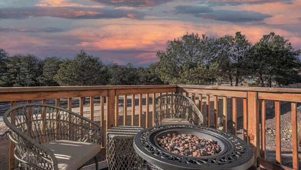 Une terrasse avec deux fauteuils en osier et un foyer extérieur.