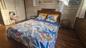 Ein Bett mit farbenfroher Blumenbettwäsche, einem Holzkopfbrett und einem Baldachin.