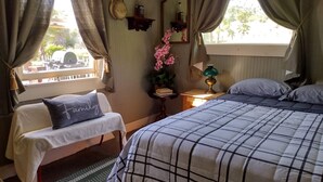 A bedroom with a bed, a bench, a nightstand, a lamp, a mirror, and a window with curtains. - Delightful Barn-Tavern Close to GIANT SEQUOIAS (Springville)