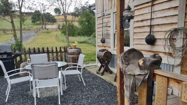 An outdoor seating area with a table and chairs, a wooden fence, and a rustic building with a wooden door. - Delightful Barn-Tavern Close to GIANT SEQUOIAS (Springville)