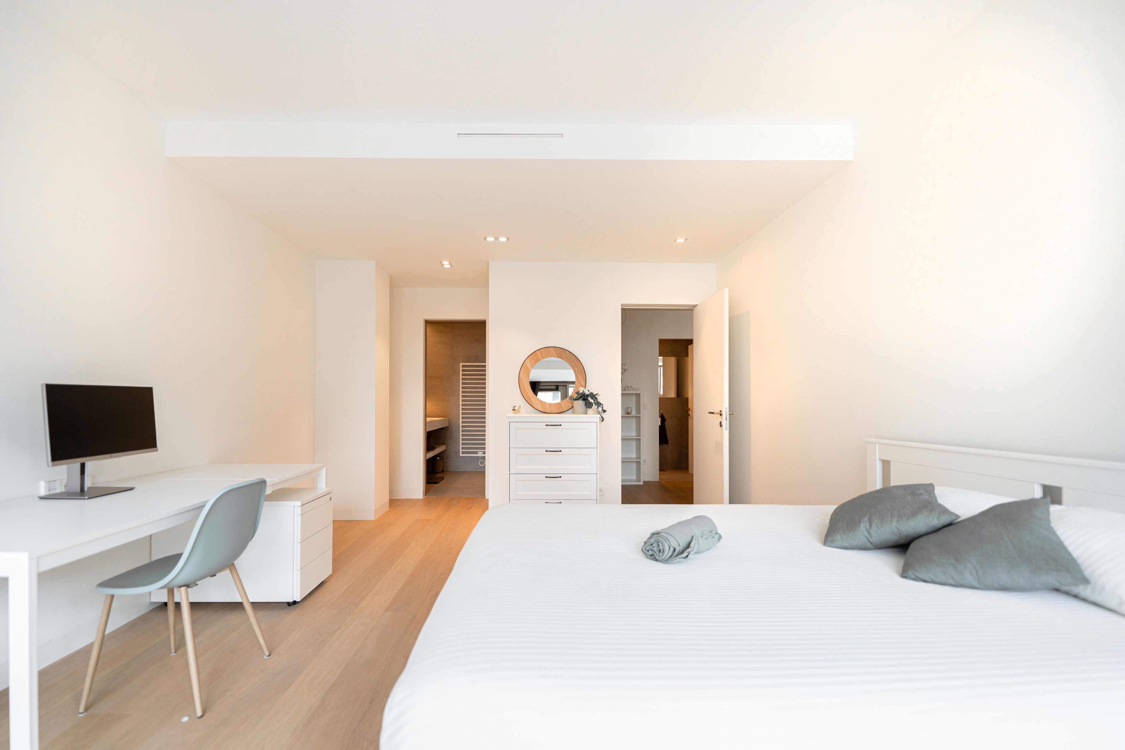A modern bedroom with a bed, bedside table, and a desk with a chair.