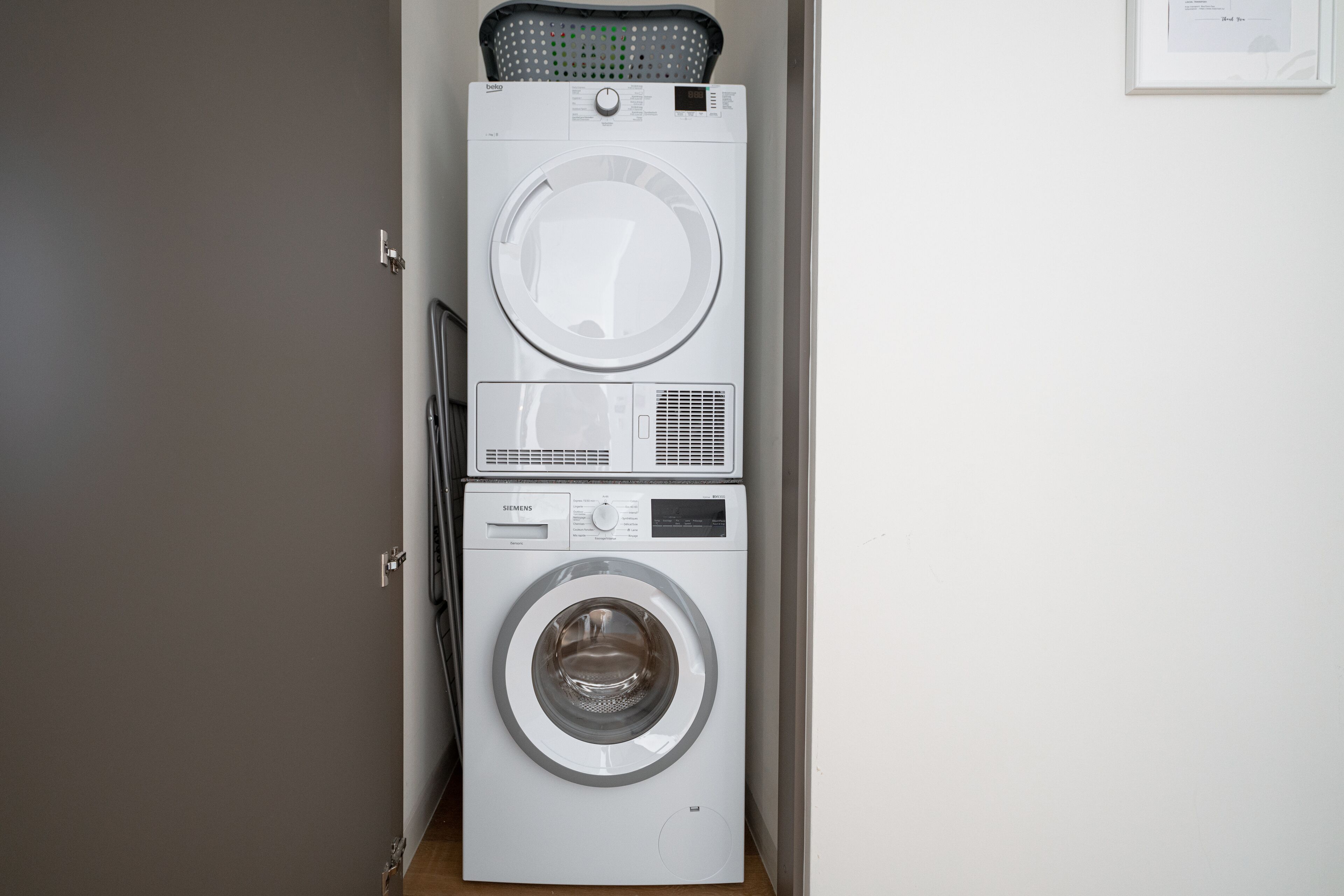 A stacked washer and dryer unit in a hallway.