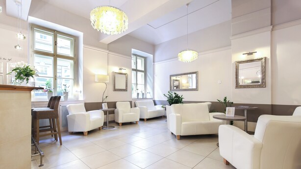 A spacious lobby with white leather sofas, a reception desk, and large windows allowing natural light. - Unitas Residence (Prague)
