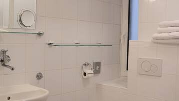 Un baño moderno con lavamanos, inodoro y estante de vidrio.