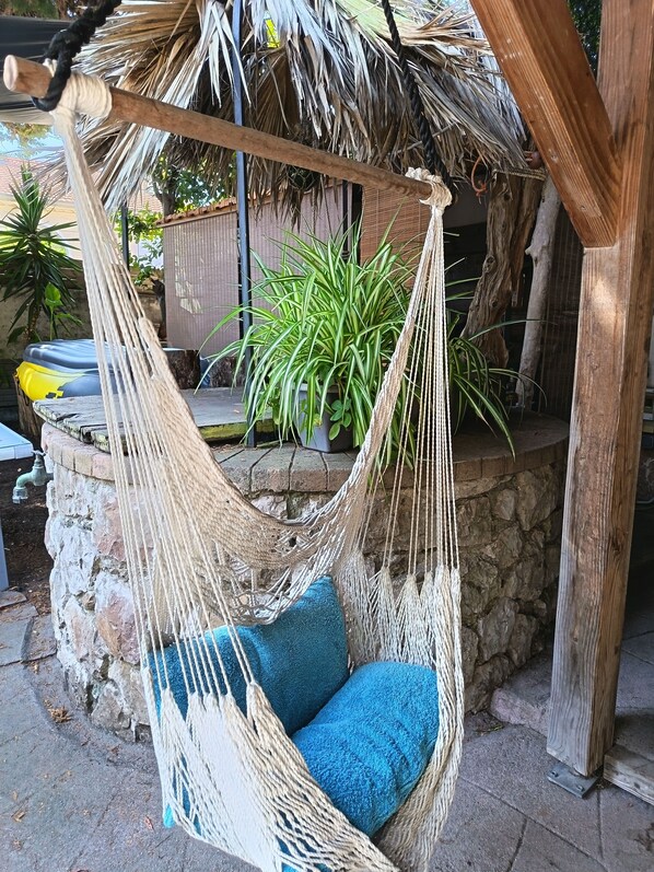 A hammock chair with blue cushions, a thatched roof structure, and potted plants in the background. - Haven of peace located 150m from Antibes' white sandy beaches- Private swimming pool (cap d'antibes)