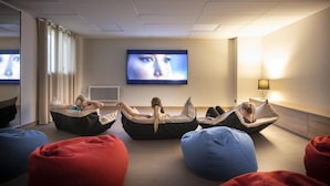 Une chambre moderne avec des fauteuils en forme de poire et un grand écran.