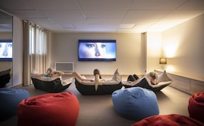 Quarto moderno com puffs e uma tela grande.