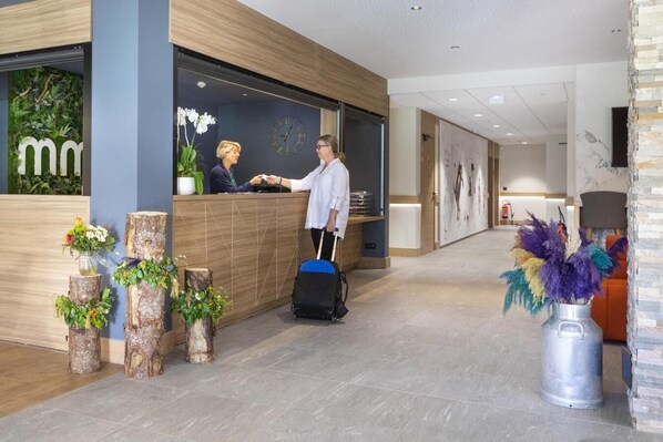 A reception area with a wooden reception desk, a clock, and a reception desk with a plant.