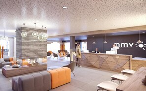A modern hotel lobby with a reception desk, seating area, and a fireplace.