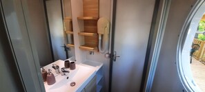 A bathroom with a white sink, two faucets, and two soap dispensers. There are wooden shelves above the sink. - Mobile home for 6 people, 3-star campground on a beautiful, quiet property with a pool (Saint-Chéron)