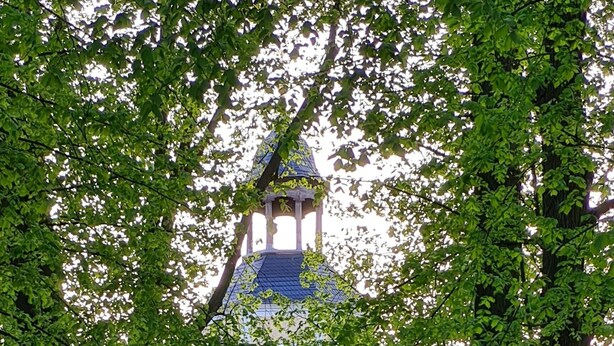 Un sentiero che conduce a un edificio con una torre imponente e una porta rossa.
