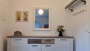 Una cucina con un armadietto bianco, una lampada a sospensione e uno specchio sul muro.