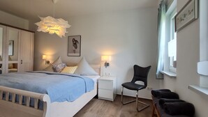 Una camera da letto con un letto, comodini, una sedia e una finestra con tende.