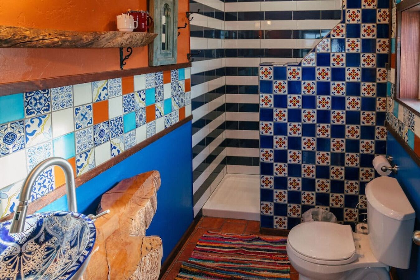 Ein Badezimmer mit einer blau und weiß gefliesten Wand, einer weißen Toilette und einer Duschkabine mit blau-weißen Fliesen.