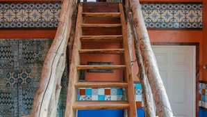 Uma escadaria de madeira com design rústico, que leva a uma porta no topo.