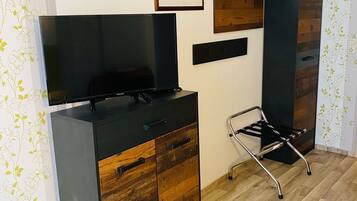 Una habitación moderna con suelo de madera, un mueble negro para televisión, un escritorio y una silla.